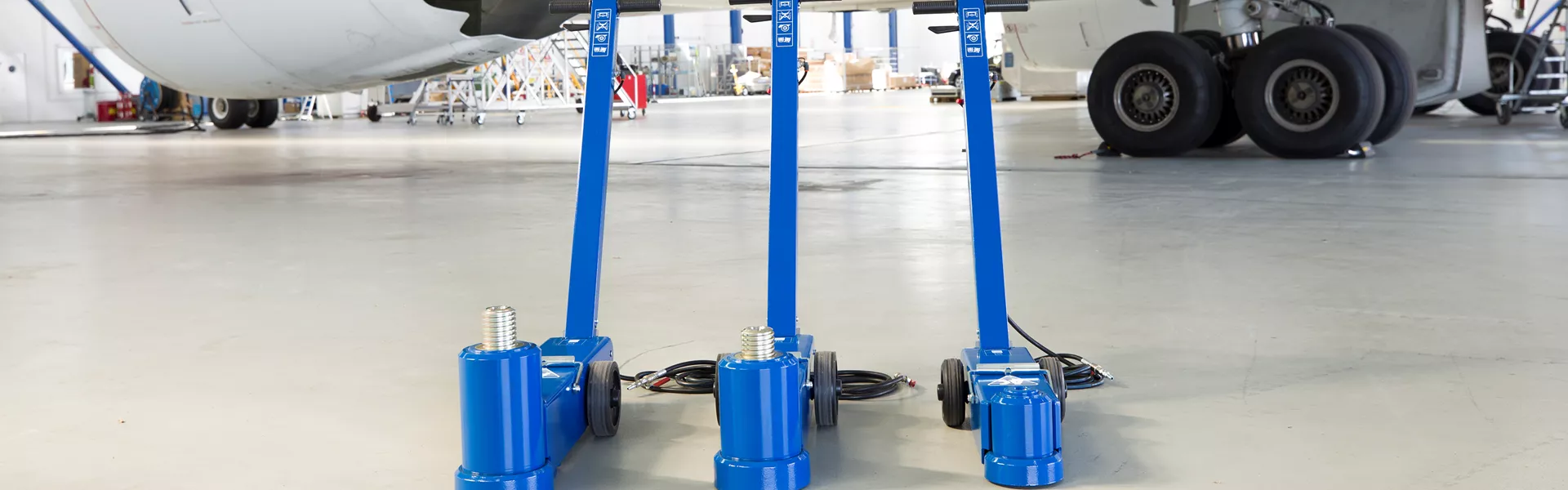 Trzy pneumatyczno-hydrauliczne podnośniki lotnicze AC Hydraulic 25-2AP pod kadłubem samolotu